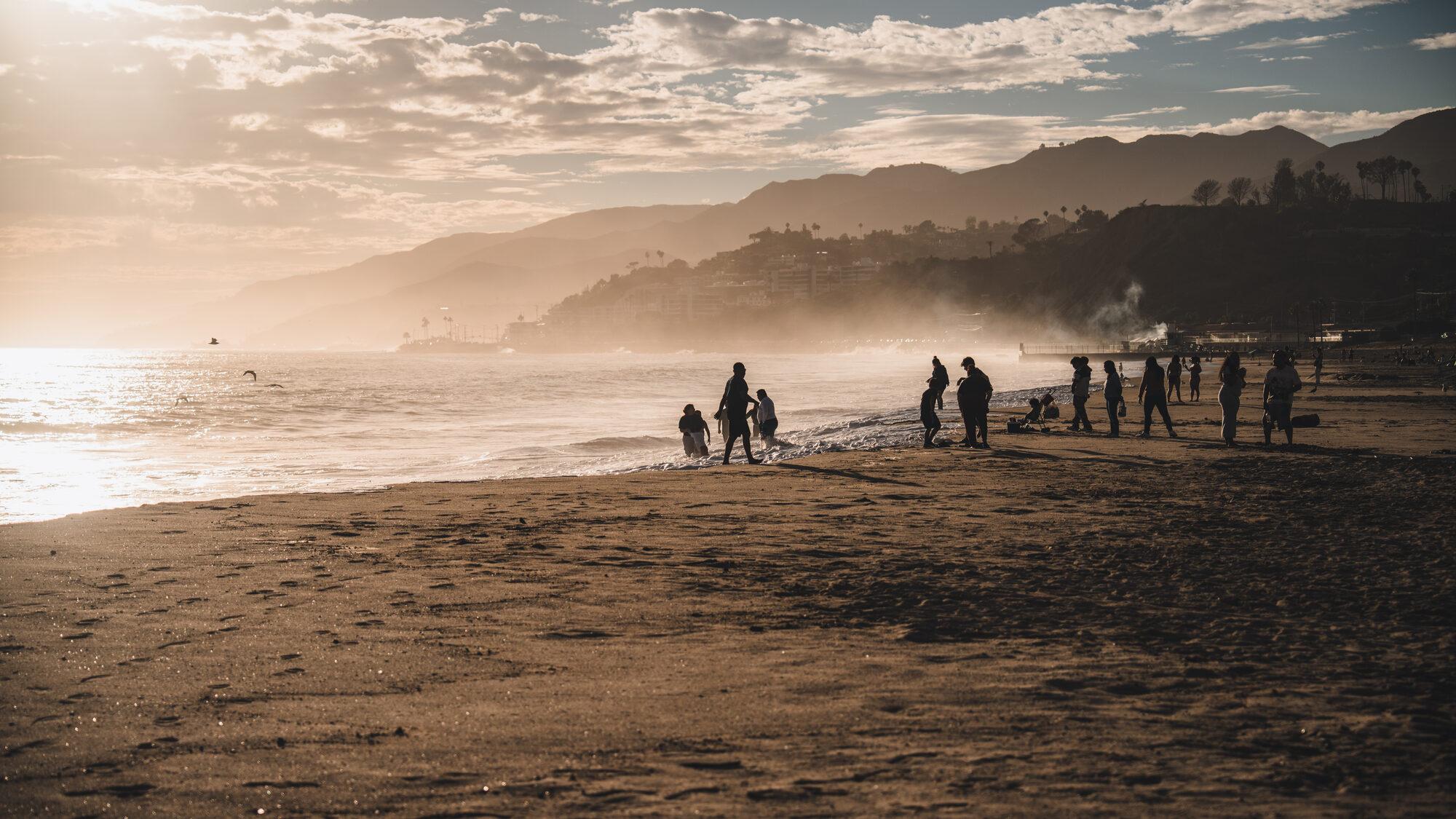 People gathered on a hazy beach at sunset